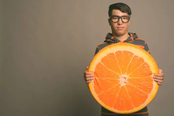 Joven asiático nerd hombre usando sudadera con capucha contra gris fondo — Foto de Stock