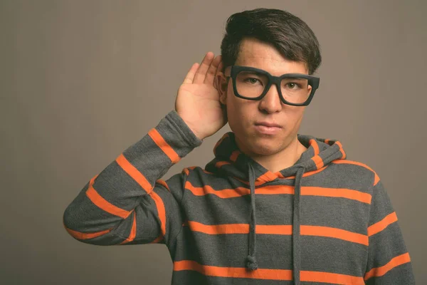 Young Asian nerd man wearing hoodie against gray background