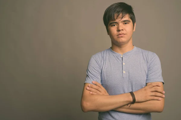 Jong aziatisch tiener jongen dragen blauw shirt tegen grijs achtergrond — Stockfoto