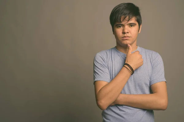 Jong aziatisch tiener jongen dragen blauw shirt tegen grijs achtergrond — Stockfoto