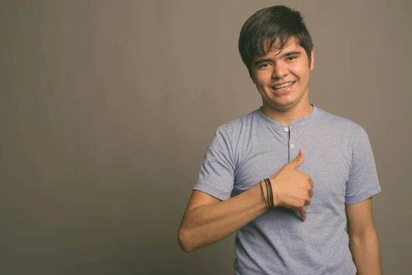 Jovem adolescente asiático vestindo camisa azul contra fundo cinza — Fotografia de Stock