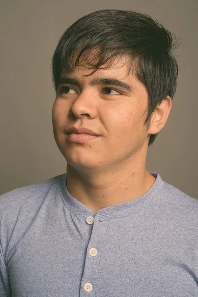 Mladý asijské dospívající chlapec nosí modré tričko proti šedé pozadí — Stock fotografie