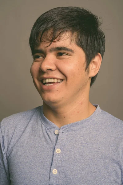 Joven adolescente asiático con camisa azul sobre fondo gris — Foto de Stock