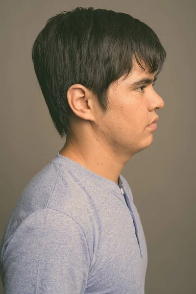 Joven adolescente asiático con camisa azul sobre fondo gris — Foto de Stock