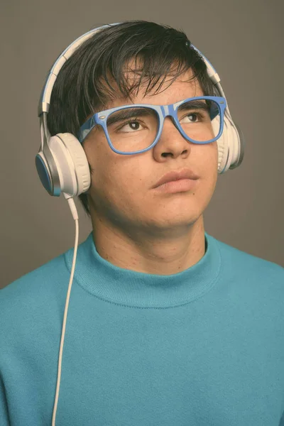在灰色背景下听音乐的亚洲少年 — 图库照片