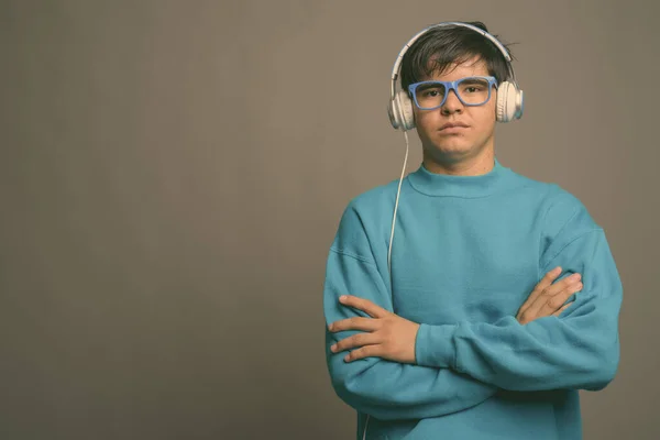 Joven adolescente asiático escuchando música sobre fondo gris — Foto de Stock