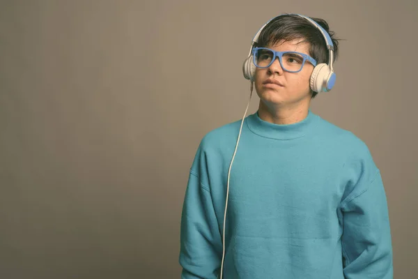 Joven adolescente asiático escuchando música sobre fondo gris — Foto de Stock