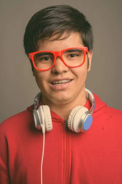Joven adolescente asiático usando auriculares contra fondo gris — Foto de Stock