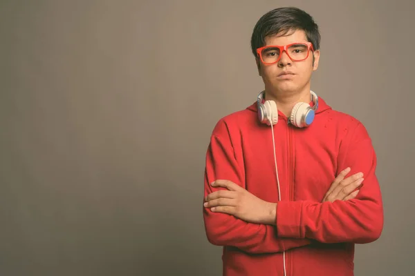 Młody Azji nastolatek chłopiec noszenie słuchawki na szarym tle — Zdjęcie stockowe