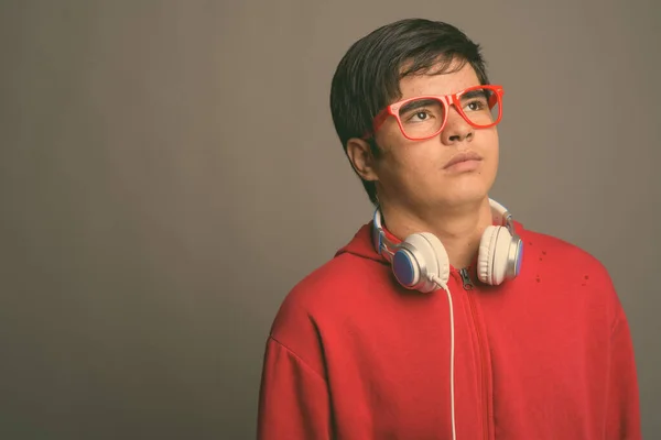 Joven adolescente asiático usando auriculares contra fondo gris —  Fotos de Stock