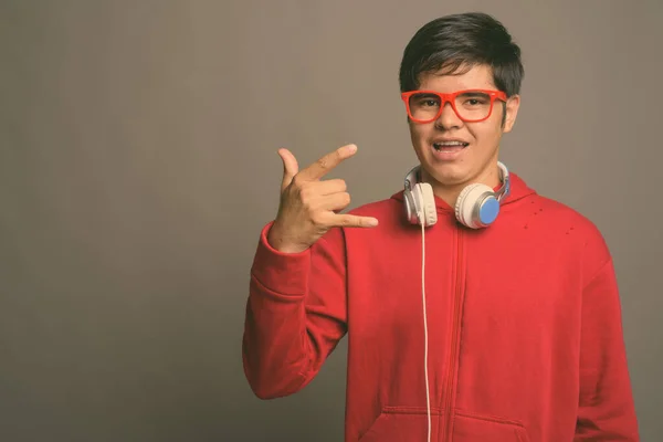 Mladý asijské dospívající chlapec nosí sluchátka na šedém pozadí — Stock fotografie