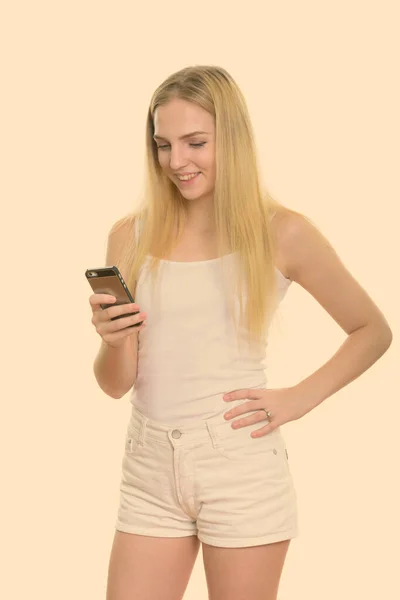 Estudio de disparo de la joven adolescente feliz sonriendo mientras se utiliza el teléfono móvil —  Fotos de Stock