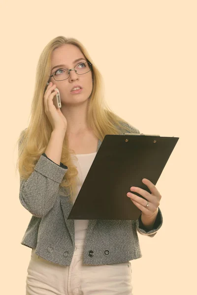Düşünceli genç iş kadını elinde bir pano ve cep telefonuyla konuşuyor. — Stok fotoğraf