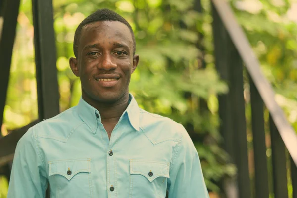 Genç mutlu zenci Afrikalı adam doğayla birlikte modern merdivenlere gülümsüyor. — Stok fotoğraf