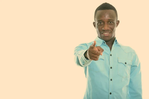 Studio shot of young happy black African man souriant tout en pointant vers la caméra — Photo