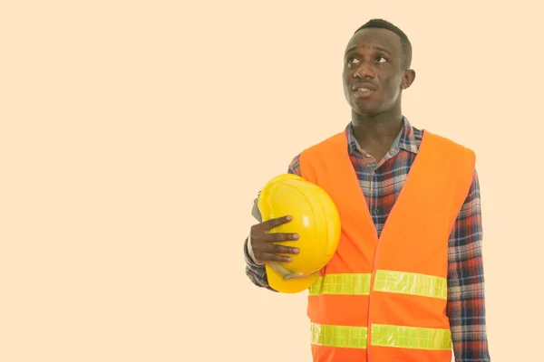 Estudio de disparo de joven africano negro trabajador de la construcción pensando mientras sostiene casco de seguridad —  Fotos de Stock