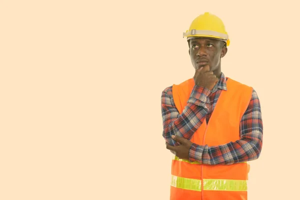 Estudio de un joven negro africano trabajador de la construcción pensando mientras mira hacia arriba —  Fotos de Stock
