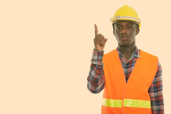 Studio schot van jonge zwarte Afrikaanse man bouwvakker wijzend vinger omhoog — Stockfoto