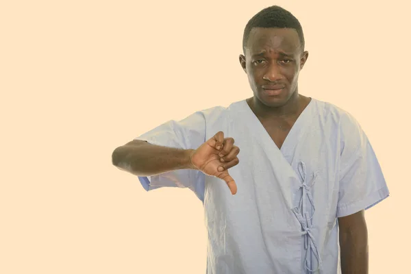 Studio shot of young black African man patient looking sad while giving thumb down — Stock Photo, Image