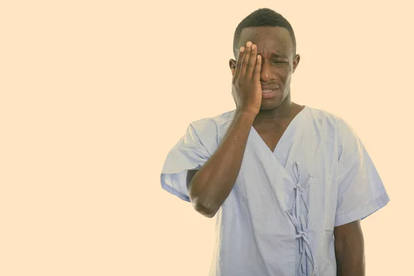 Studio shot of young black African man patient looking sad while covering face — Stock Photo, Image