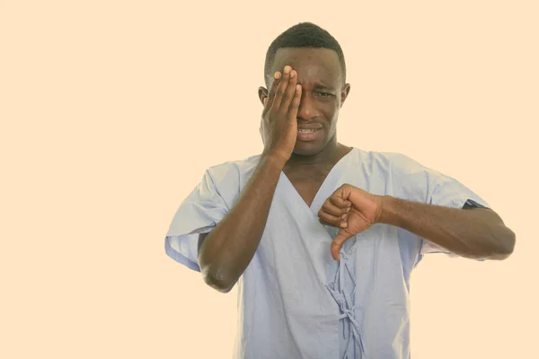 Estudio toma de joven negro africano hombre paciente buscando triste mientras cubre la cara y dando pulgar hacia abajo — Foto de Stock