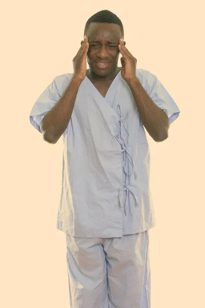 Estudio disparo de joven estresado negro africano hombre paciente de pie mientras tiene dolor de cabeza —  Fotos de Stock