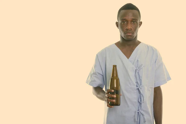 Studio shot of young black African man patient holding bottle of beer — Stock Photo, Image