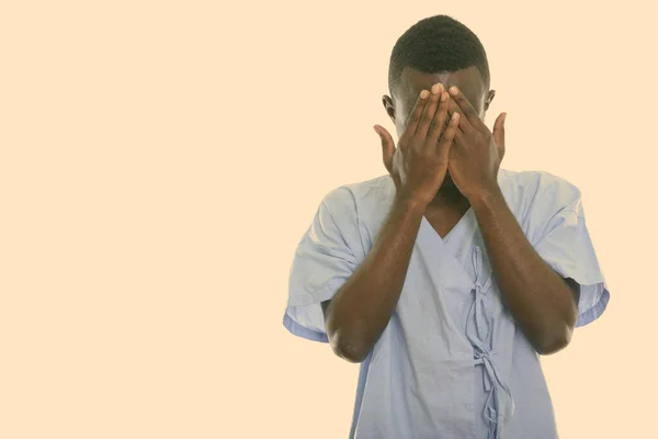 Studio shot of young black African man patient covering face with both hands — Stock Photo, Image