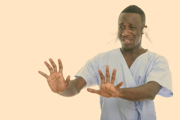 Stüdyoda, hasta görünen, kulaklarında mendil olan ve dur işaretini iki eliyle gösteren Afrikalı genç bir adam görülüyor. — Stok fotoğraf