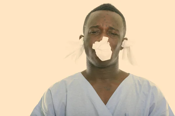 Studio shot of young black African man patient looking sick with tissues in his ears and nose — Stock Photo, Image