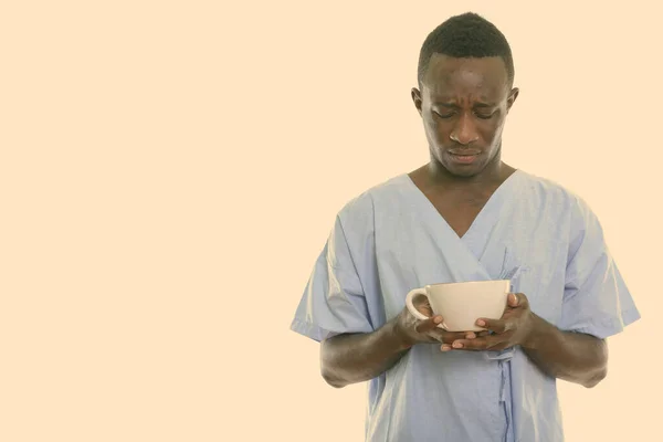 非洲悲伤欲绝的年轻黑人病人拿着咖啡杯的摄影棚镜头 — 图库照片
