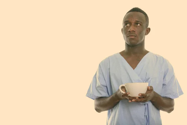 Estudio disparo de joven negro africano hombre paciente pensando mientras sostiene la taza de café —  Fotos de Stock