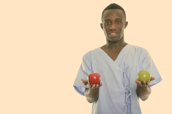 Estudio disparo de joven feliz negro africano paciente sonriendo mientras sostiene manzana roja y manzana verde —  Fotos de Stock