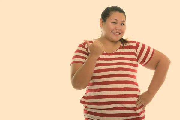 젊고 뚱뚱 한 아시아 여성이 웃으며 엄지손가락을 내밀고 있는 스튜디오 촬영 — 스톡 사진
