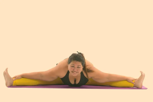 Studio shot van jong gelukkig vet aziatische vrouw glimlachen en splitsen van haar benen terwijl kijken naar camera — Stockfoto
