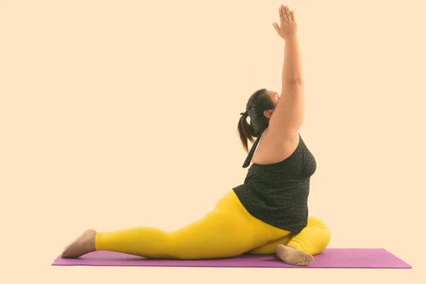 Студийный снимок молодой толстой азиатской женщины растягивая ноги и дотягиваясь, делая представления йоги — стоковое фото