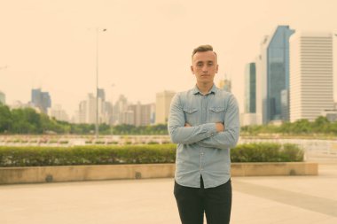 Sarışın, genç ve yakışıklı bir adam parkta dinleniyor.