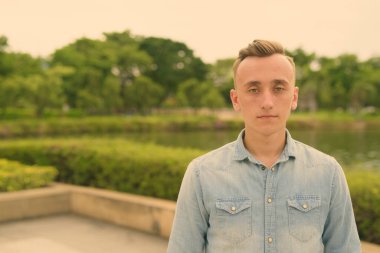 Sarışın, genç ve yakışıklı bir adam parkta dinleniyor.