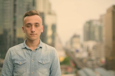 Sarışın, yakışıklı genç bir adam şehrin manzarasına karşı.