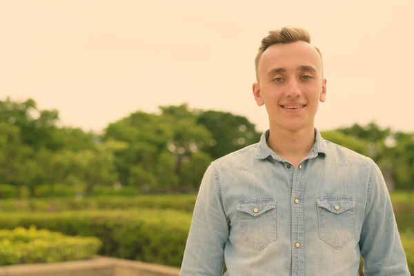 Junger schöner Mann mit blonden Haaren entspannt sich im Park — Stockfoto