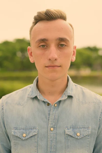 Jovem homem bonito com cabelo loiro relaxante no parque — Fotografia de Stock