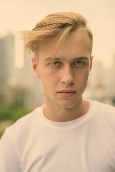 Jeune homme beau aux cheveux blonds contre vue sur la ville — Photo