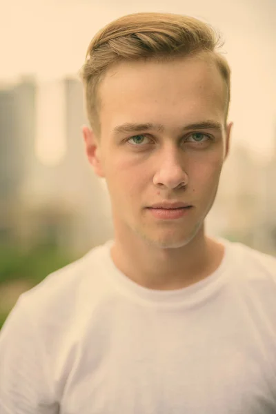 Junger schöner Mann mit blonden Haaren gegen den Blick auf die Stadt — Stockfoto