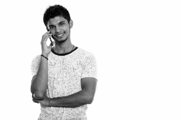 Estudio de tiro de joven feliz indio sonriendo mientras habla en el teléfono móvil — Foto de Stock