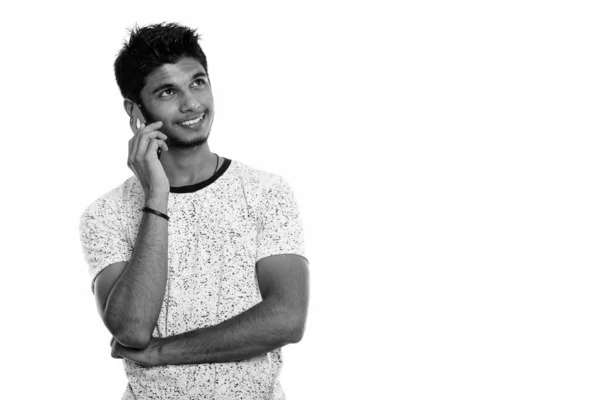 Зйомки молодого щасливого індійського чоловіка, який посміхається і розмовляє по мобільному телефону, коли думає — стокове фото