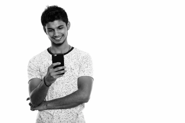 スタジオショットの若い幸せなインド人男性の笑顔ながら、携帯電話を使用して — ストック写真