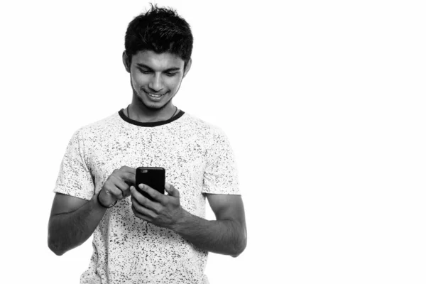 Estúdio tiro de jovem feliz indiano homem sorrindo ao usar o telefone móvel — Fotografia de Stock