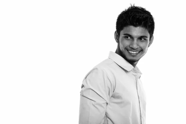 Studioaufnahme eines jungen glücklichen indischen Mannes, der lächelt und denkt, während er zurückblickt — Stockfoto