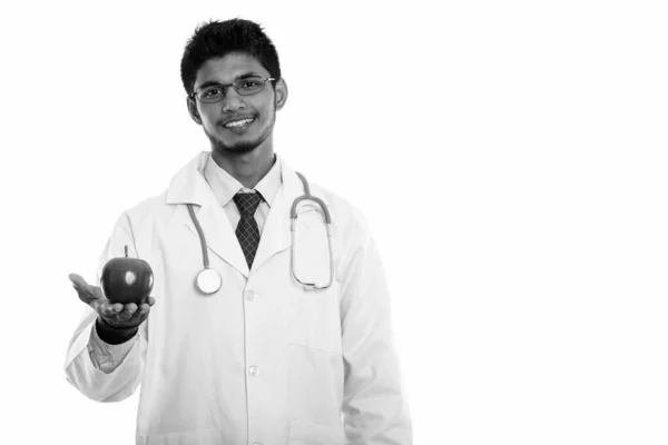 Estudio disparo de joven feliz indio hombre médico sonriendo mientras sostiene manzana roja — Foto de Stock