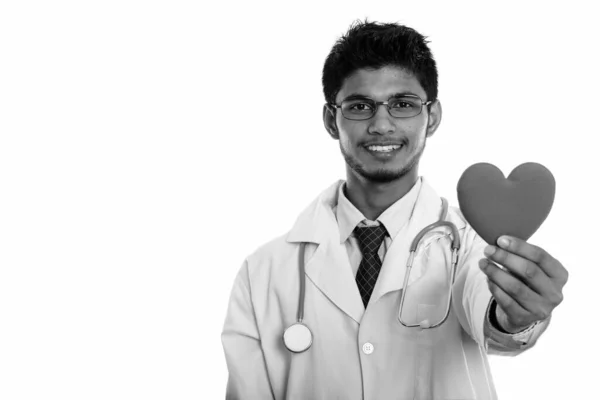 Estudio disparo de joven feliz indio hombre médico sonriendo mientras sostiene el corazón rojo —  Fotos de Stock